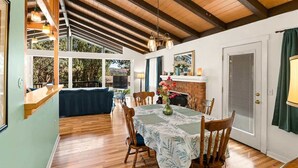 Un comedor con una mesa dispuesta para cuatro, sillas de madera, chimenea y vistas al exterior.