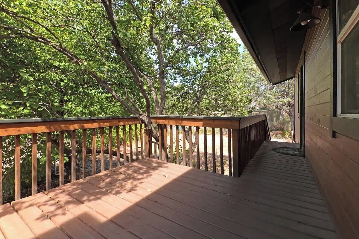 A wooden deck with a railing, surrounded by trees.