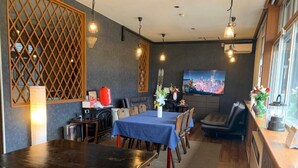 Un espace repas avec une longue table, des sièges rembourrés de couleur rouge et un téléviseur fixé au mur.