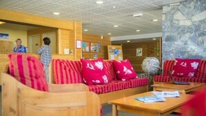 A lobby with wooden seating, a stone wall, and a reception area.
