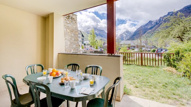 Una mesa de comedor con sillas, alimentos para el desayuno y vistas a montañas y un estacionamiento.