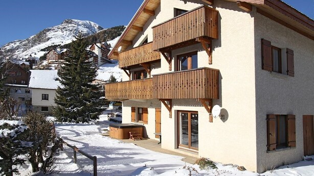 A two-story building with wooden balconies, a snow-covered landscape, and a mountain in the background.