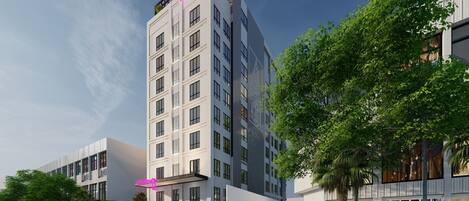 A modern hotel with a prominent neon sign, multiple floors, and a parking area with cars.