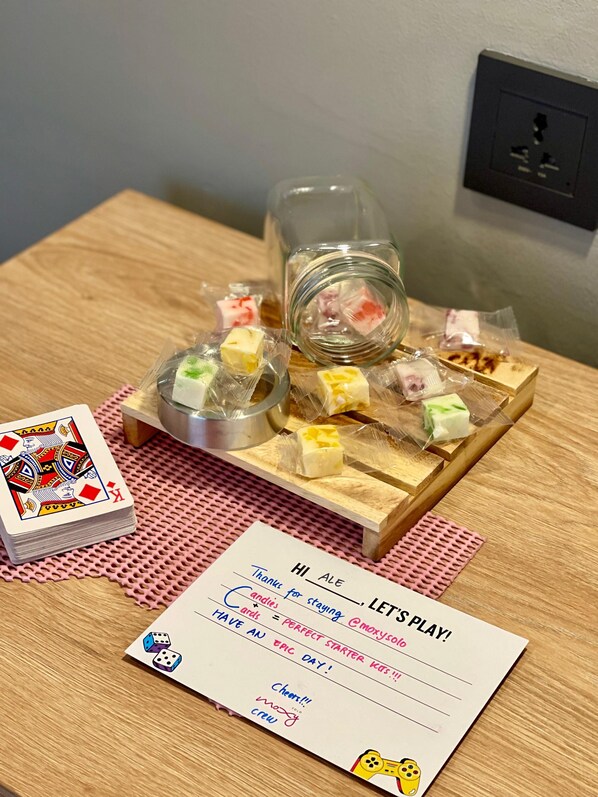 Una mesa de madera con un juego de cartas dispuesto, incluyendo una baraja, un tarro y caramelos envueltos.