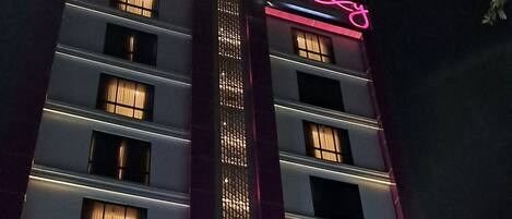 Et hotel med flere etager, oplyst skiltning og en moderne facade.