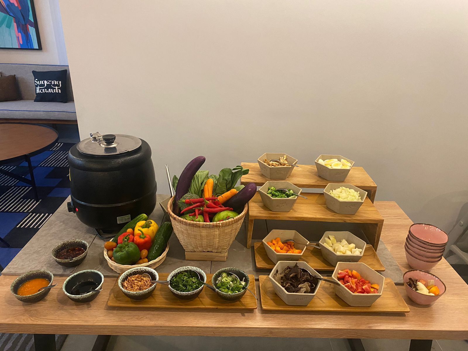 A buffet table with various food items and a large black container, likely a barbecue grill, on the left.