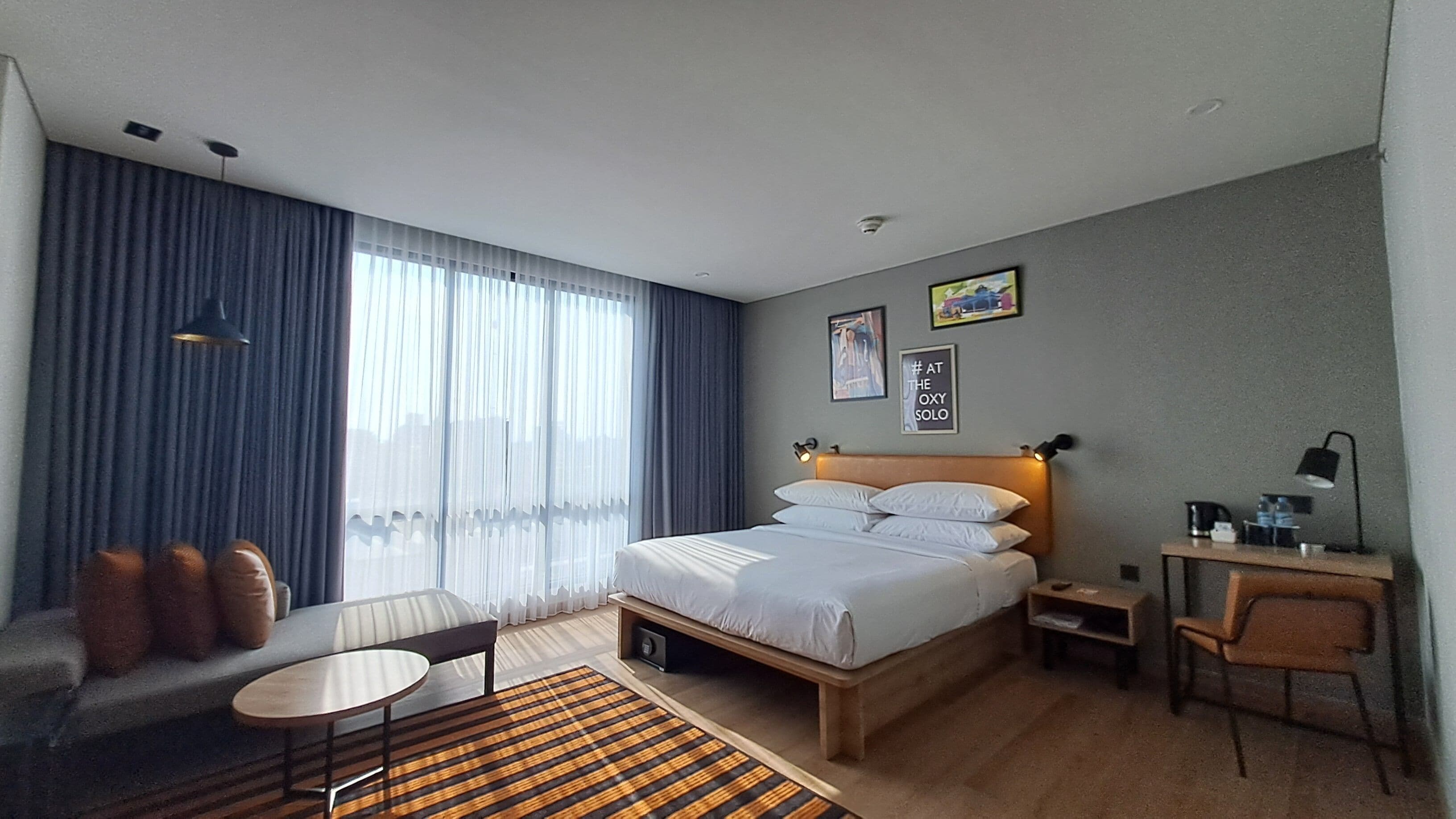 Een moderne hotelkamer met een groot bed, een bank, een bureau en een kleine tafel.