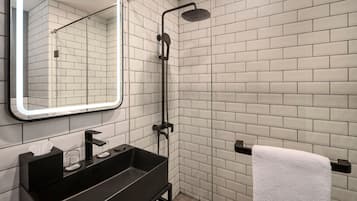 A modern bathroom with a black sink, a mirror with a light, and a shower.
