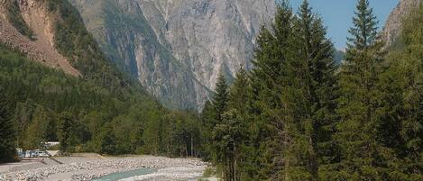 Ein Fluss, der durch eine gebirgige Landschaft mit felsigen Ufern und dichten Wäldern fließt.