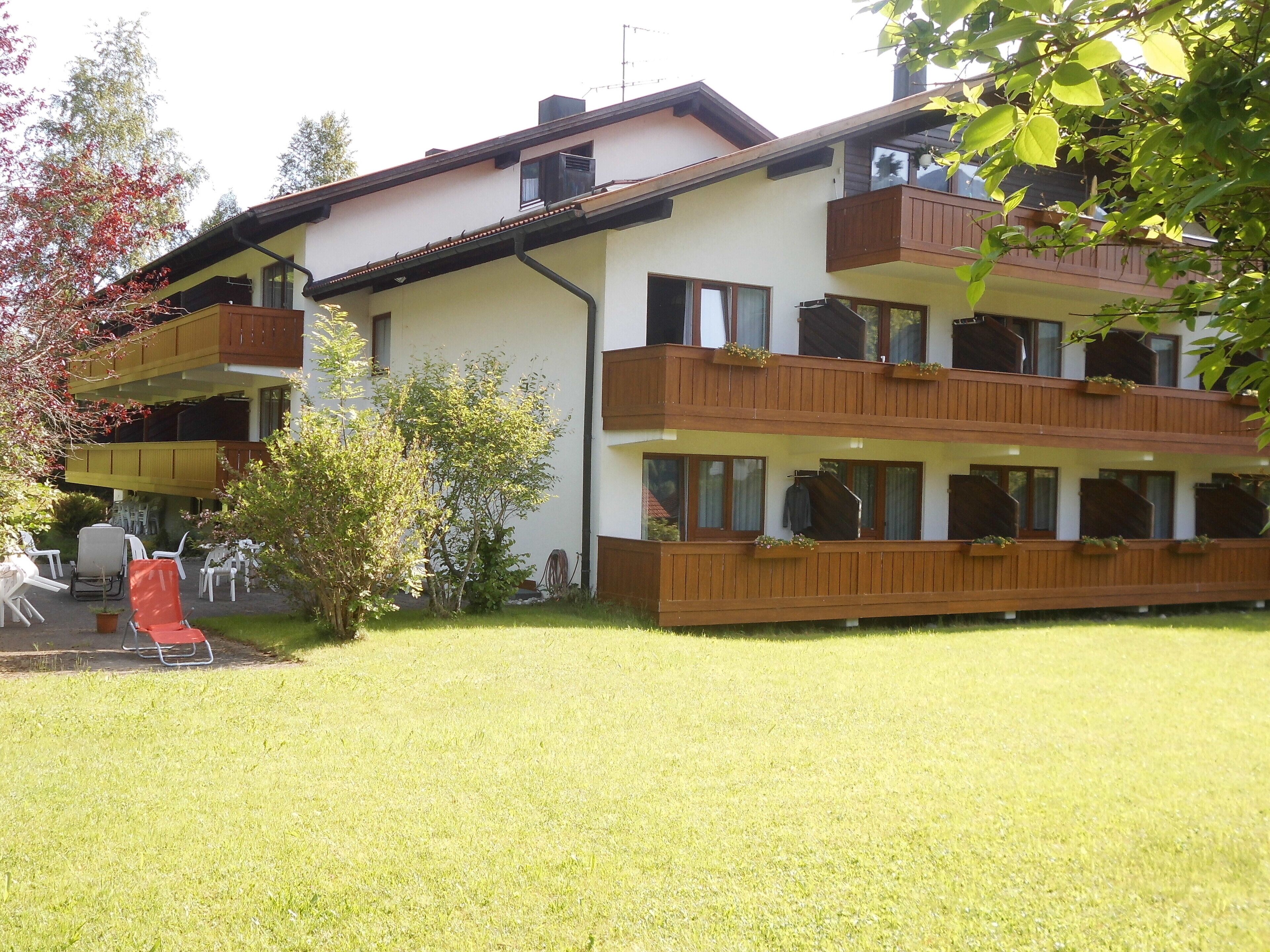 A multi-story building with balconies, outdoor seating, and a well-maintained lawn.