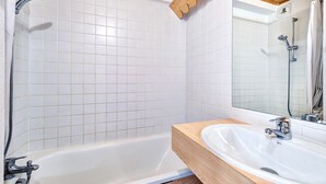 A modern bathroom with a white tiled wall, a wooden vanity, a white sink, and a bathtub. - Proche des Pistes + Téléski | Duplex avec Balcon (Risoul)