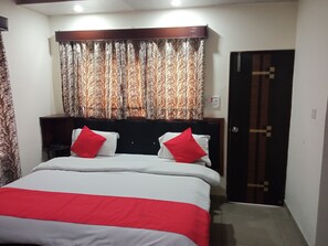A bedroom with a bed, two red pillows, a headboard, a curtain, and a door. - Moon Peak Cottage (Dharamshala)