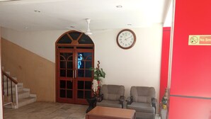 Une pièce avec une porte en bois, une horloge, deux canapés, une table basse et un escalier.