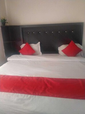A bed with a white and red bedspread, two red pillows, and a dark headboard. - Moon Peak Cottage (Dharamshala)