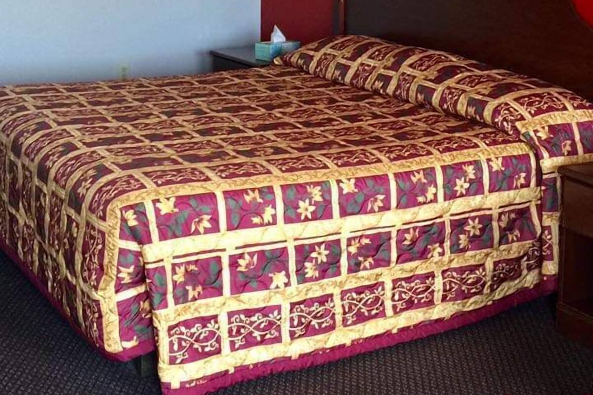 Ein Hotelzimmer mit einem großen Bett, einem Nachttisch, einer Lampe und einem gerahmten Bild an der Wand.