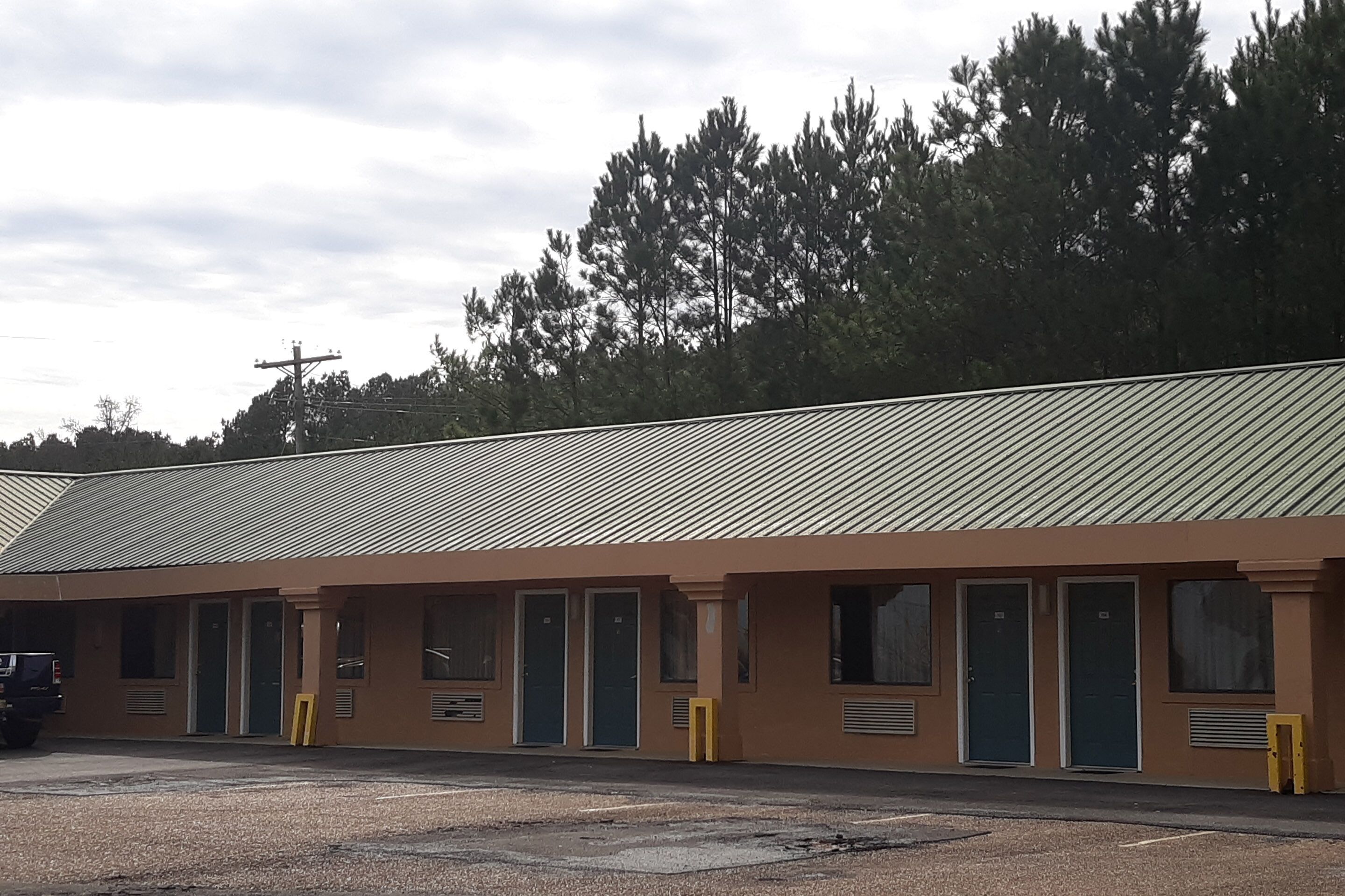 A motel with a row of rooms, each with a door and a window.