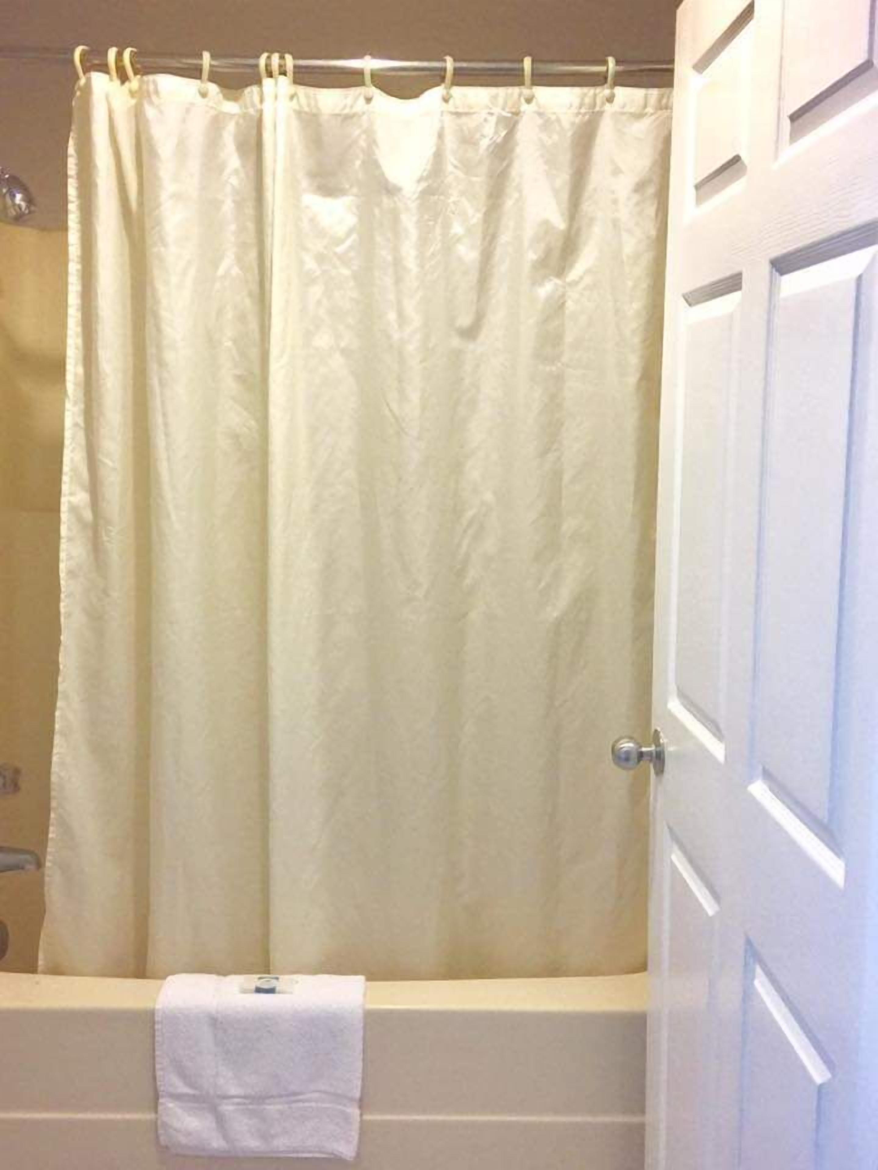 Une salle de bain avec une baignoire, un rideau de douche et une serviette accrochée au mur.