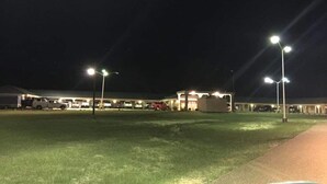 Um estacionamento à noite, com vários carros e um edifício ao fundo.