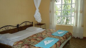 A room with a bed, a small table, and a window with curtains.