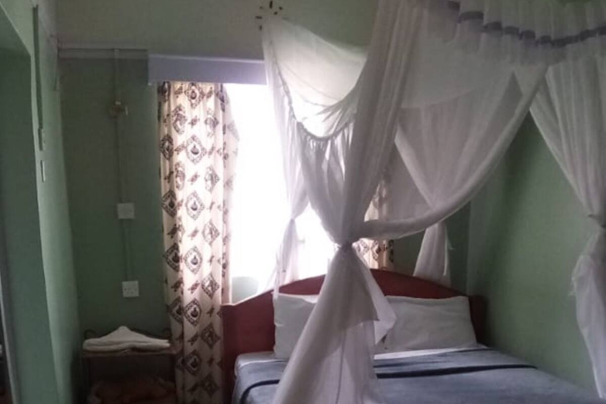 A room with a bed under a canopy, a small table, and a window with curtains.