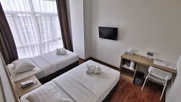 A hotel room with two beds, a TV, a desk with a chair, and a window with curtains.