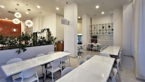 A modern cafe with white tables and chairs, a green sign, and a fire hose sign. - Green World Hotel (Semporna)