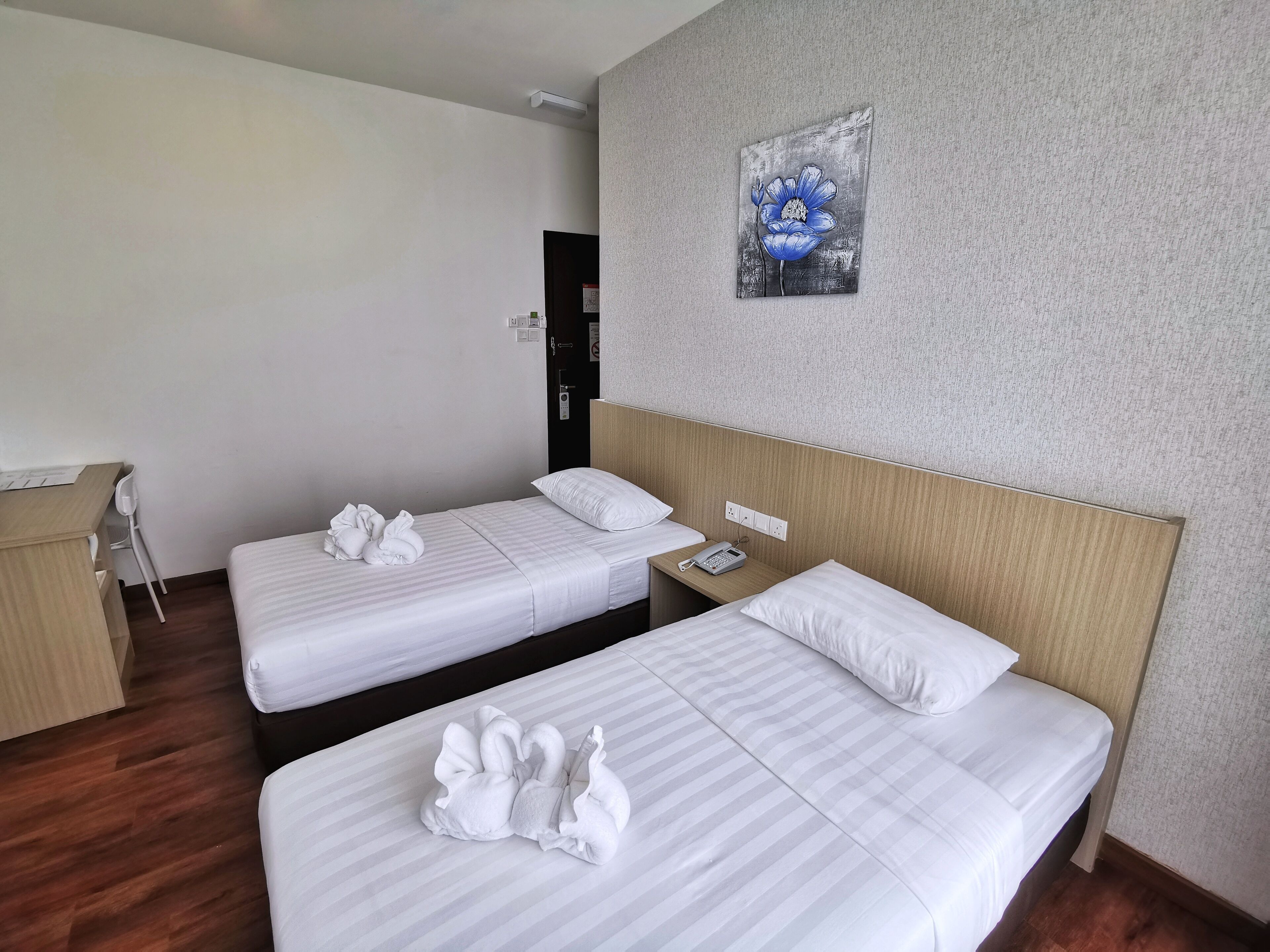 Een hotelkamer met twee bedden, een bureau en een schilderij aan de muur.