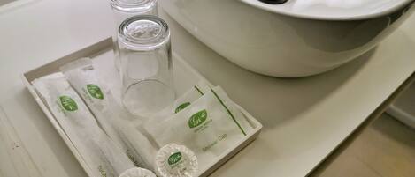 A bathroom sink with a large basin and a tray containing two soap bars and two glass bottles.