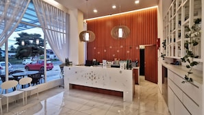 A modern hotel lobby with a reception desk, seating area, and a view of the street. - Green World Hotel (Semporna)