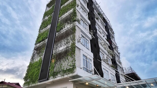A modern building with a glass entrance and a balcony with greenery. - Green World Hotel (Semporna)