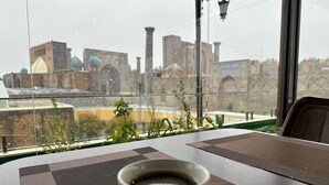 En kop kaffe på et bord med udsigt til en historisk bygning gennem et vindue.