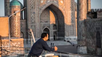 A man leaning on a railing with a historic building in the background.