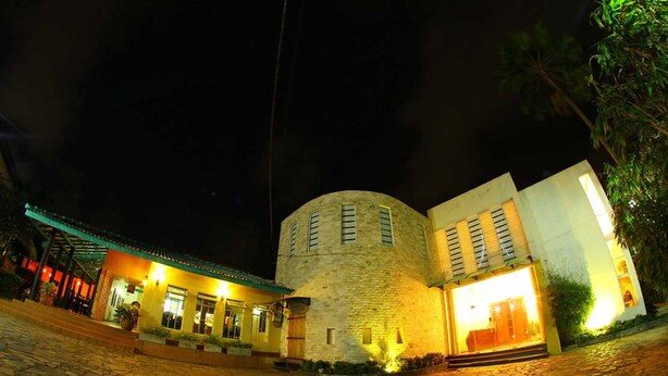 A stone building with a round tower, a covered entrance, and a well-lit entrance. - Sanoreech Hotel (Negombo)