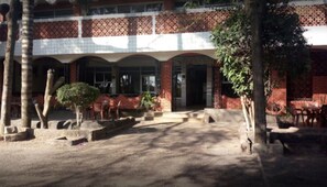 A building with a tiled facade, a covered entrance, and outdoor seating. - Lakeside Tourist Lodge (Naivasha)