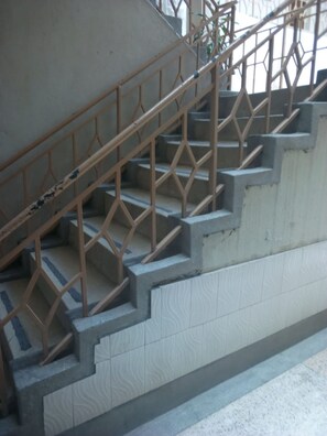 A staircase with a metal railing and tiled walls.