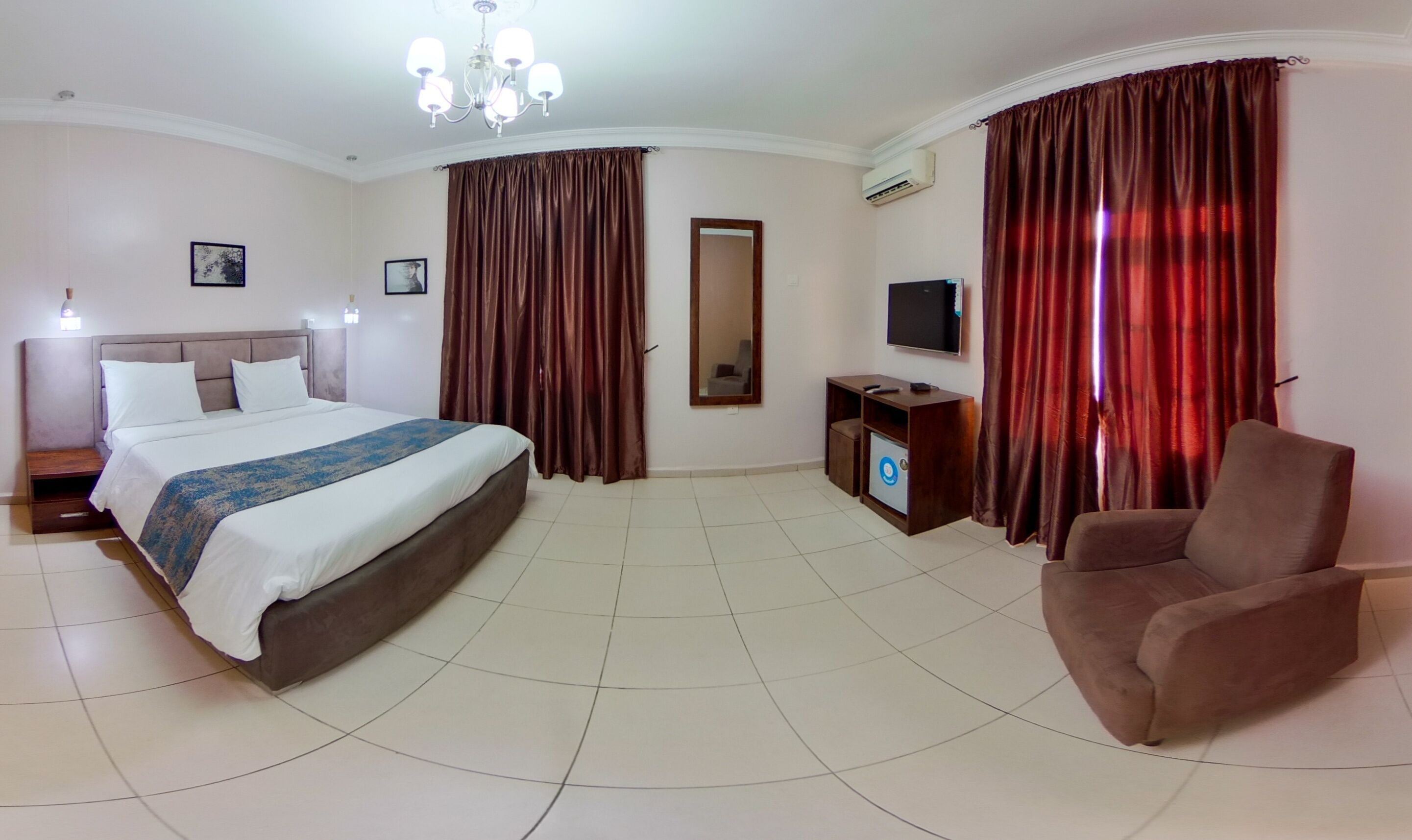 A hotel room with a bed, a TV, a chair, and a desk.
