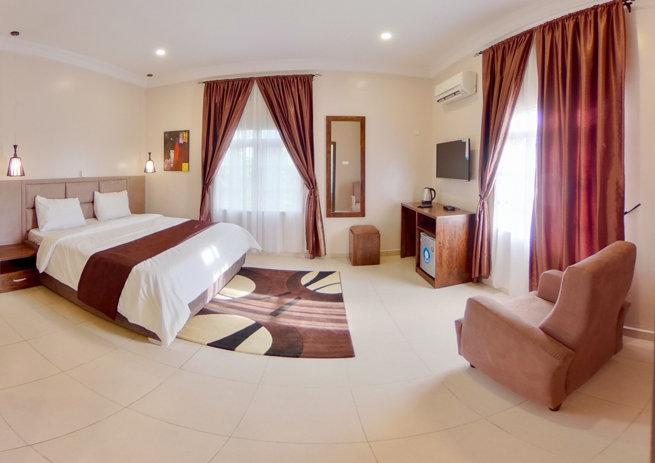 A modern hotel room with a large bed, a desk, a chair, and a TV.