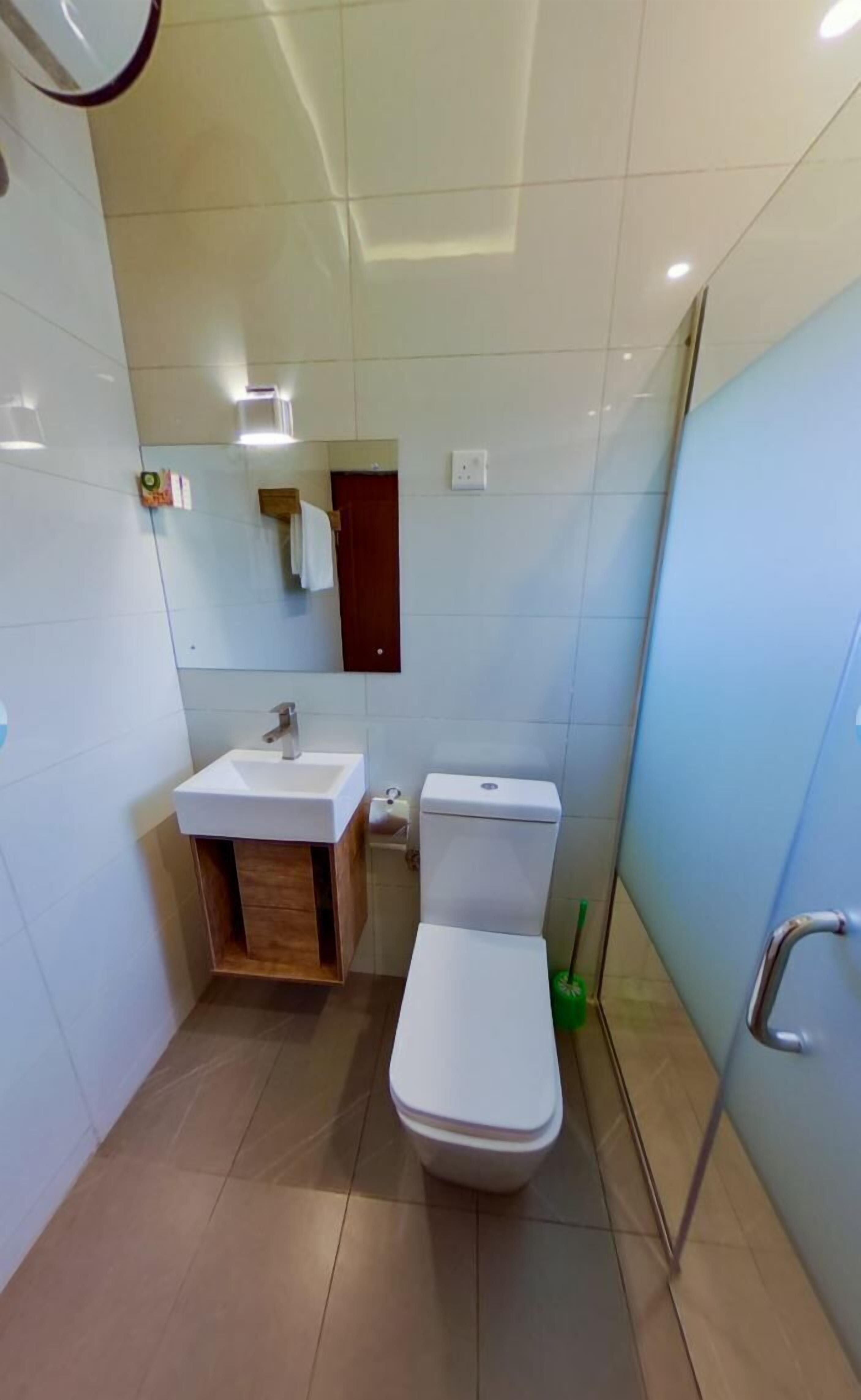 A modern bathroom with a white sink, toilet, and a mirror above the sink.