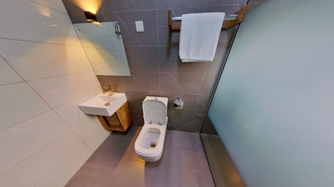 A modern bathroom with a toilet, sink, and mirror.