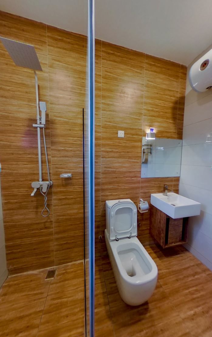 Ein modernes Badezimmer mit einer Glasdusche, einer Toilette und einem Waschbecken mit Holzschrank.