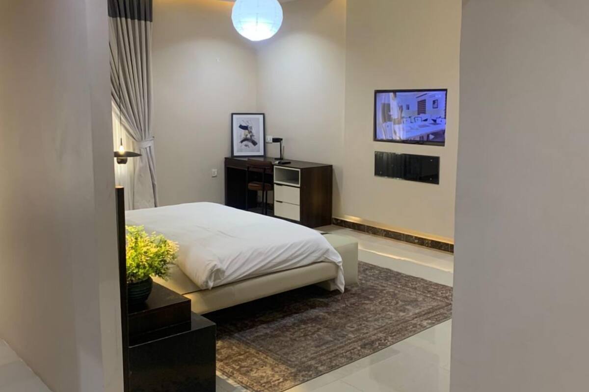A modern bedroom with a bed, bedside tables, a TV, and a ceiling light.