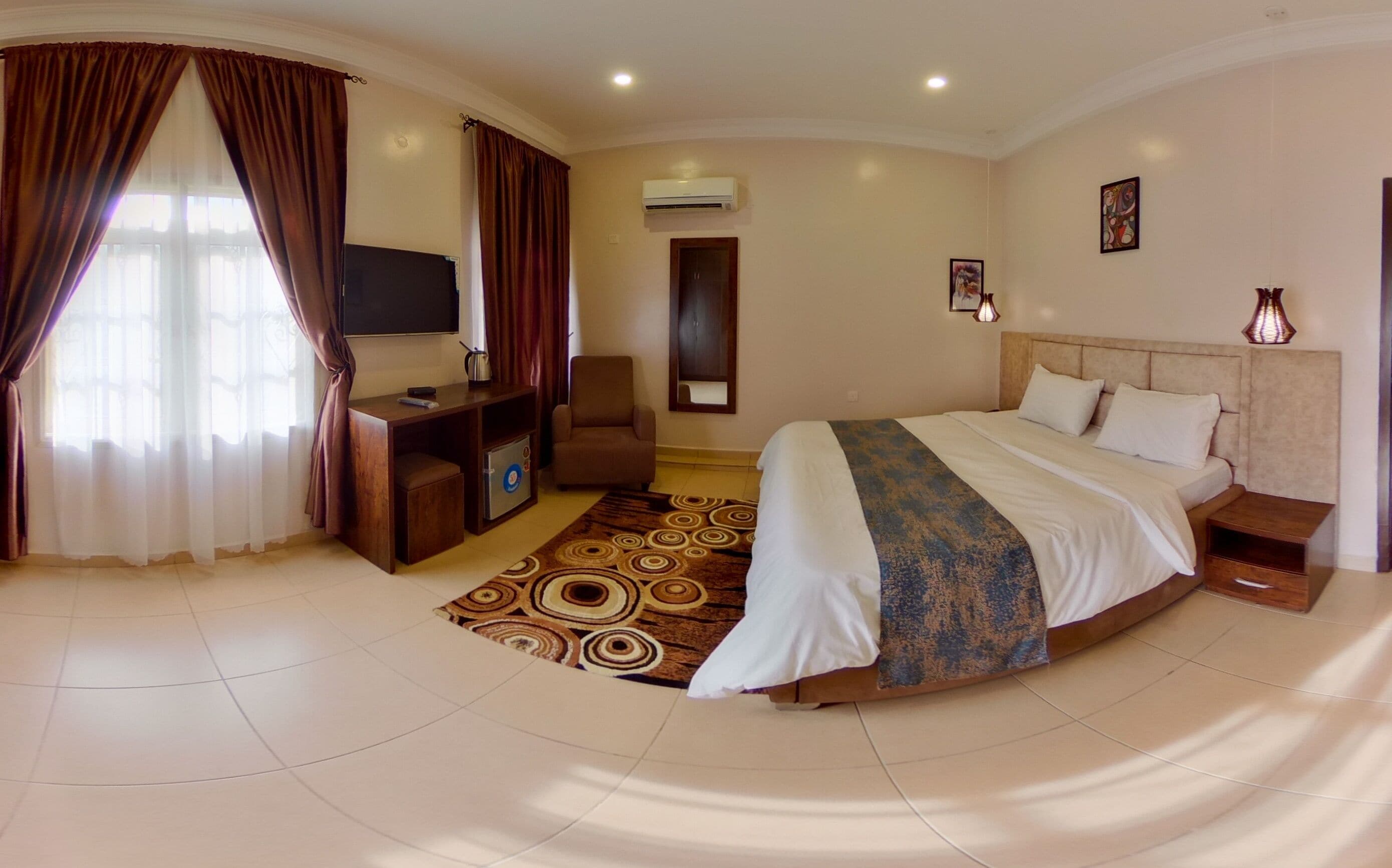 Une chambre d’hôtel équipée d’un lit, d’un bureau, d’une chaise, d’une télévision, d’un climatiseur et d’une porte.