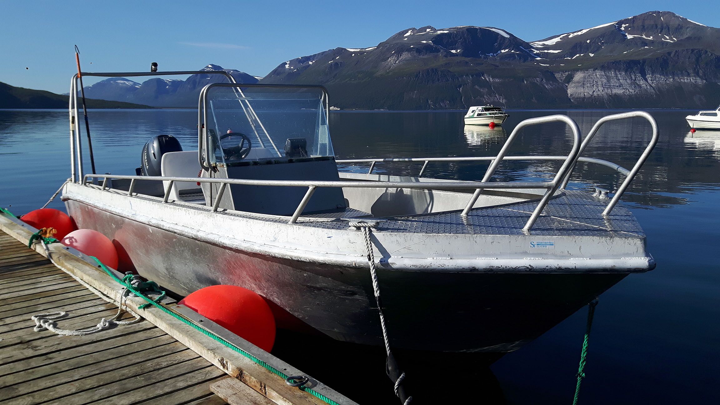 A boat docked at a pier with mountains in the background.