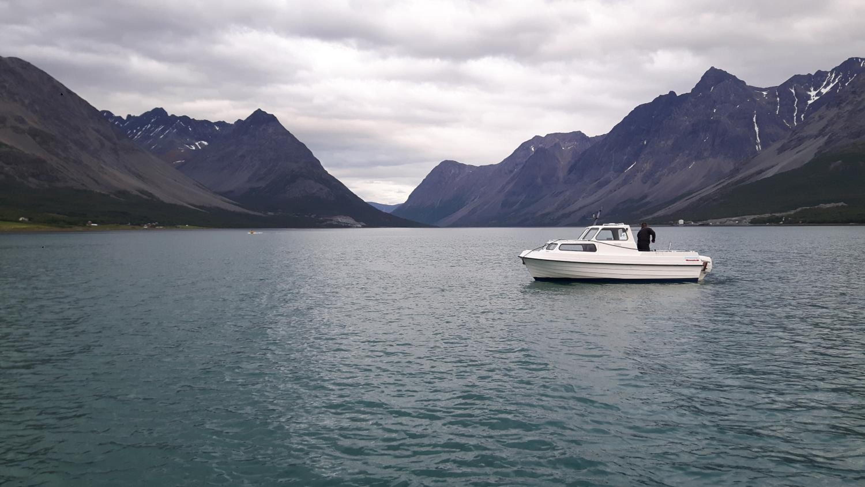 A boat on a calm lake with mountains in the background.