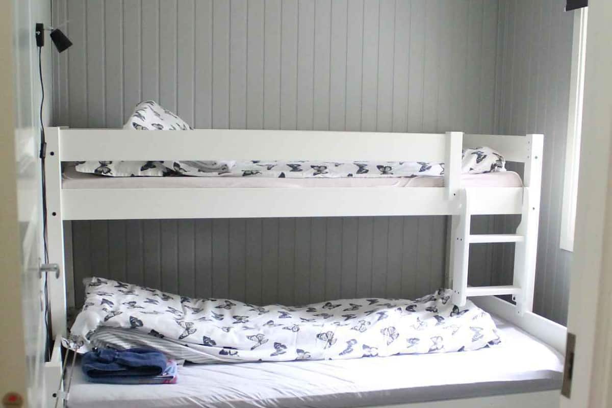 A bunk bed room with a desk and a small rug.