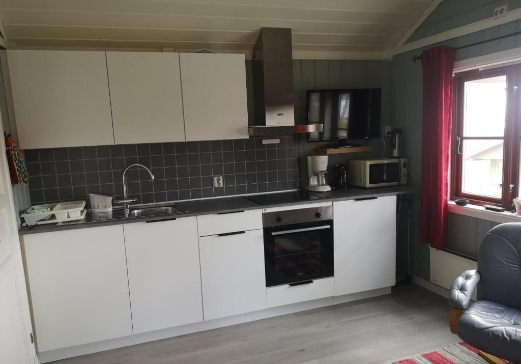 Een kleine keuken met witte kasten, een magnetron en een inbouwoven.