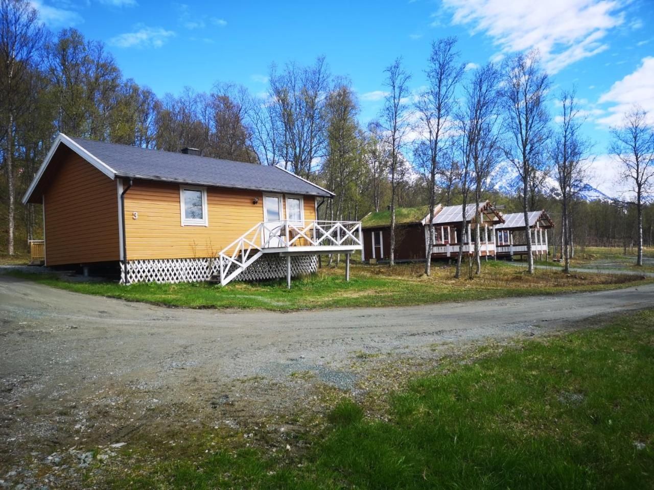 A wooden cabin with a porch, surrounded by trees and a clear sky.