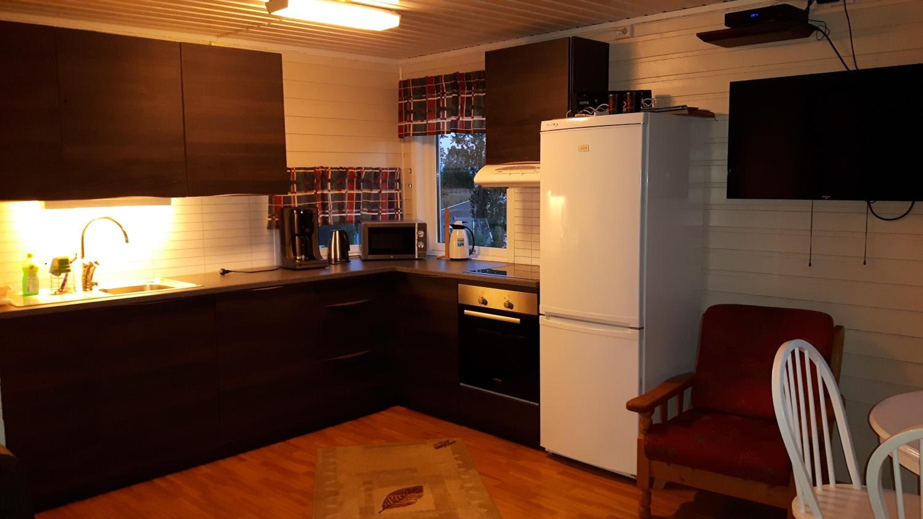 A compact kitchen with a refrigerator, stove, microwave, and sink.