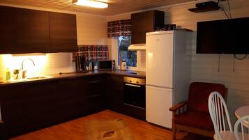 A compact kitchen with a refrigerator, stove, microwave, and sink.