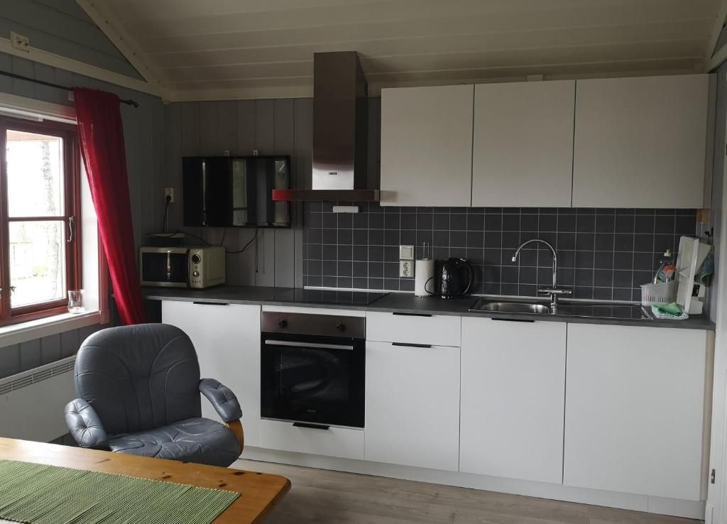 A compact kitchen with white cabinets, a black stove, a microwave, and a sink.
